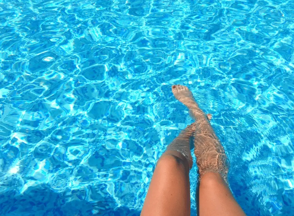 Tips for pool owners and algae. Image of a clear pool with a woman's legs in it.