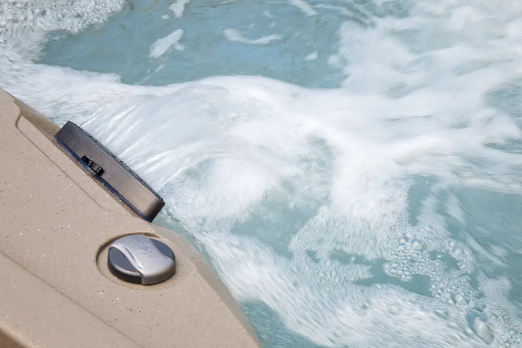 Close-up view of Fantasy Spas Drift waterfall feature with bubbling water and smooth sand-colored shell