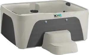 Front view of the Fantasy Spas Enamor Premier in Sand shell with Charcoal cabinet, featuring a waterfall and stainless steel jet trim.