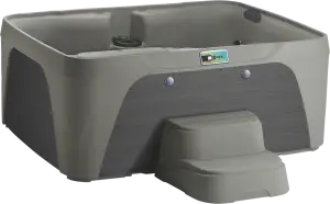 Front view of the Fantasy Spas Enamor Premier in Taupe shell with Charcoal cabinet, showing waterfall feature and stainless steel jet accents.