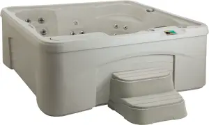 Front view of the Fantasy Spas Entice hot tub in Sand finish, showing lounge seat, waterfall feature, and stainless steel jet layout.