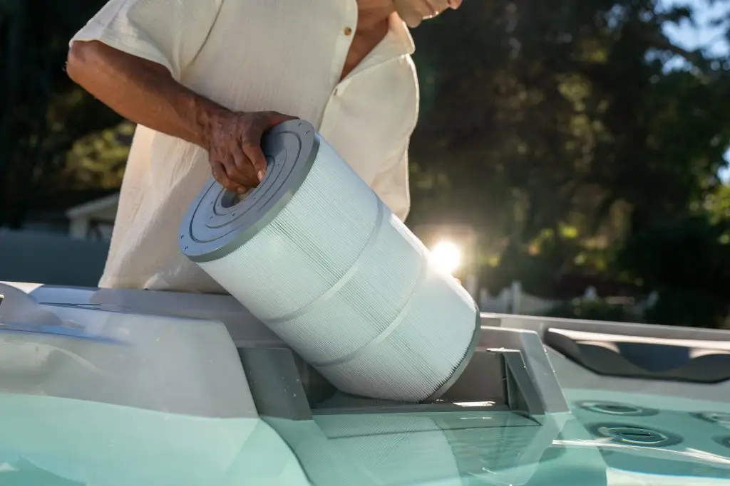 Person removing a filter cartridge from a Sundance 880 Series Optima hot tub at Blackthorne Spas