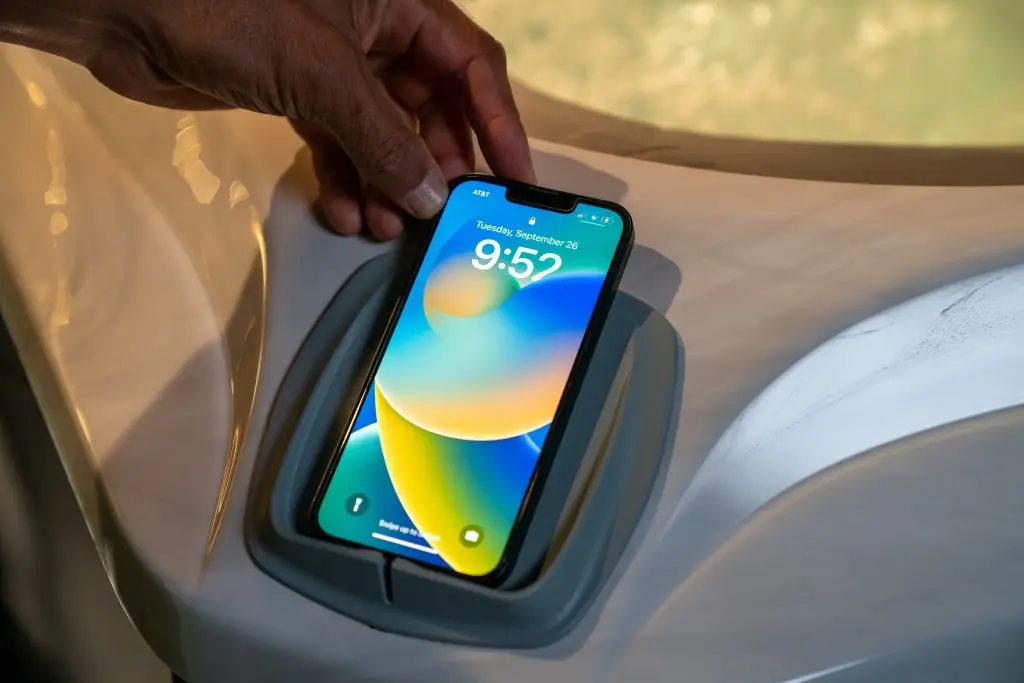 Smartphone placed in a built-in wireless charging dock on a Sundance 880 Series hot tub at Blackthorne Spas